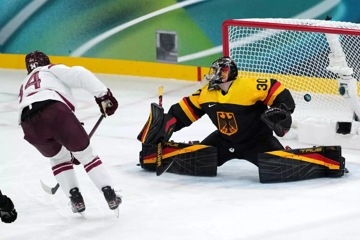 Latvia's Eduards Tralmaks (34) scores against Germany goalkeeper Philipp Grubauer (30) during the third period of a men's ice hockey preliminary round match at the 2026 Winter Olympics, in Milan, Italy, Saturday, Feb. 14, 2026. (AP Photo/Carolyn Kaster)