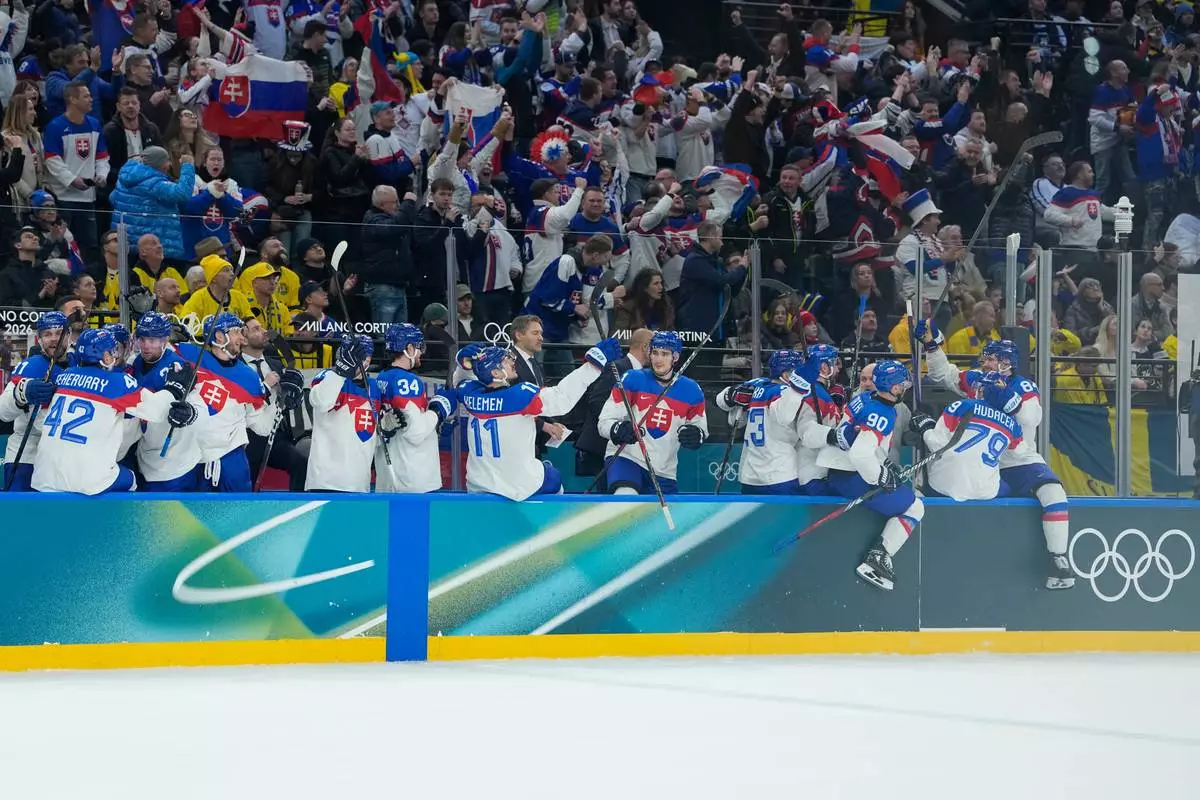 Slovakia players celebrate after their teammate Slovakia's Dalibor Dvorsky scores his side's third goal during a preliminary round match of men's ice hockey between Sweden and Slovakia at the 2026 Winter Olympics, in Milan, Italy, Saturday, Feb. 14, 2026. (AP Photo/Petr David Josek)