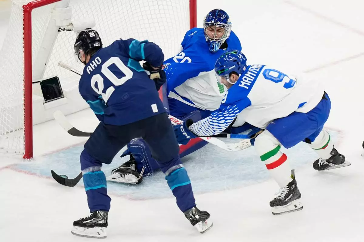 Finland's Sebastian Aho, left, scores his sides first goal past Italy's goalkeeper Damian Clara during a preliminary round match of men's ice hockey between Finland and Italy at the 2026 Winter Olympics, in Milan, Italy, Saturday, Feb. 14, 2026. (AP Photo/Hassan Ammar)