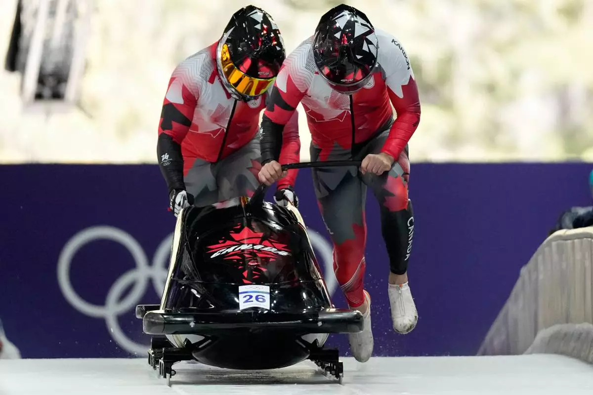 Canada's Taylor Austin, right, and Shaquille Murray-Lawrence start for a two man bobsled run at the 2026 Winter Olympics, in Cortina d'Ampezzo, Italy, Monday, Feb. 16, 2026. (AP Photo/Alessandra Tarantino)