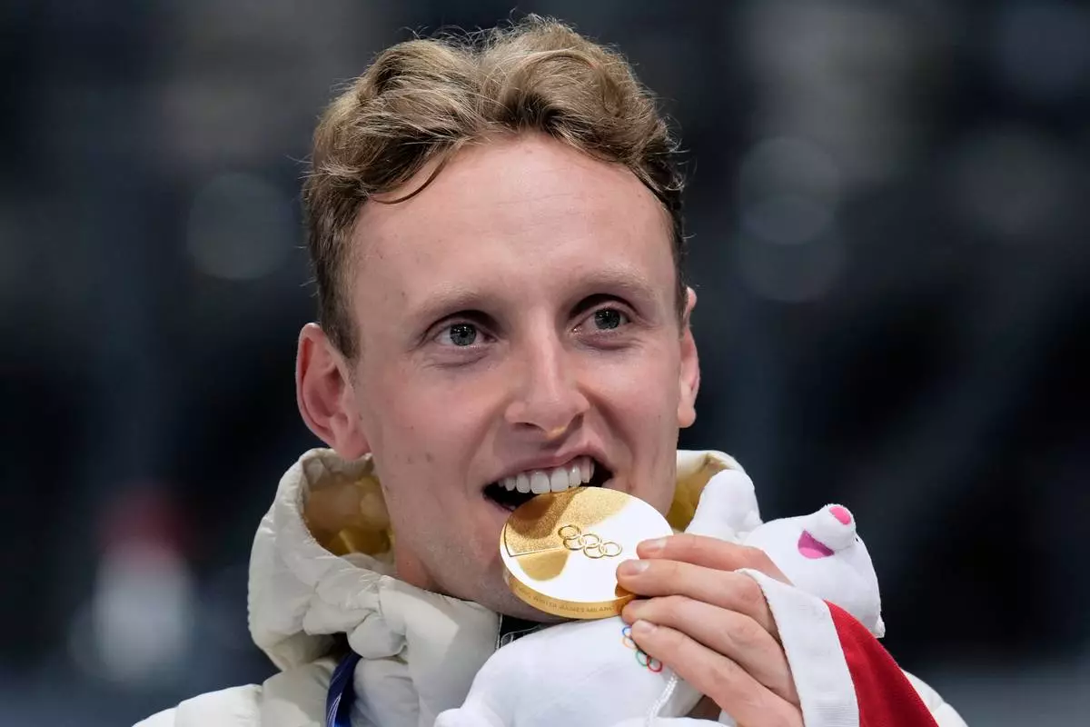Sander Eitrem of Norway bites his gold medal on the podium after the men's 5,000 meters speedskating race at the 2026 Winter Olympics, in Milan, Italy, Sunday, Feb. 8, 2026. (AP Photo/Luca Bruno)