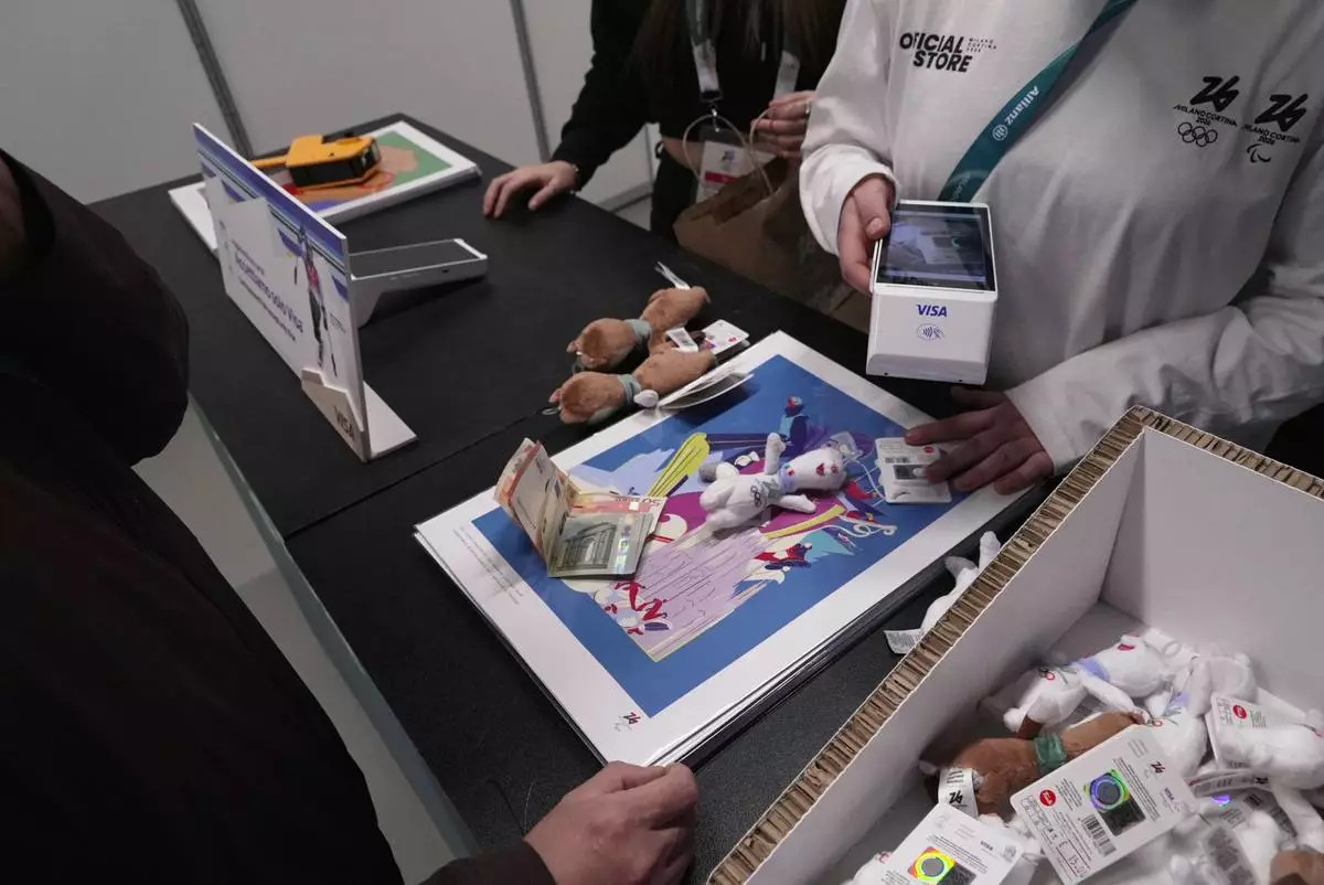 People buy Milo and Tina, the mascots of the 2026 Winter Olympics, in Milan, Tuesday, Feb. 10, 2026. (AP Photo/Brittany Peterson)