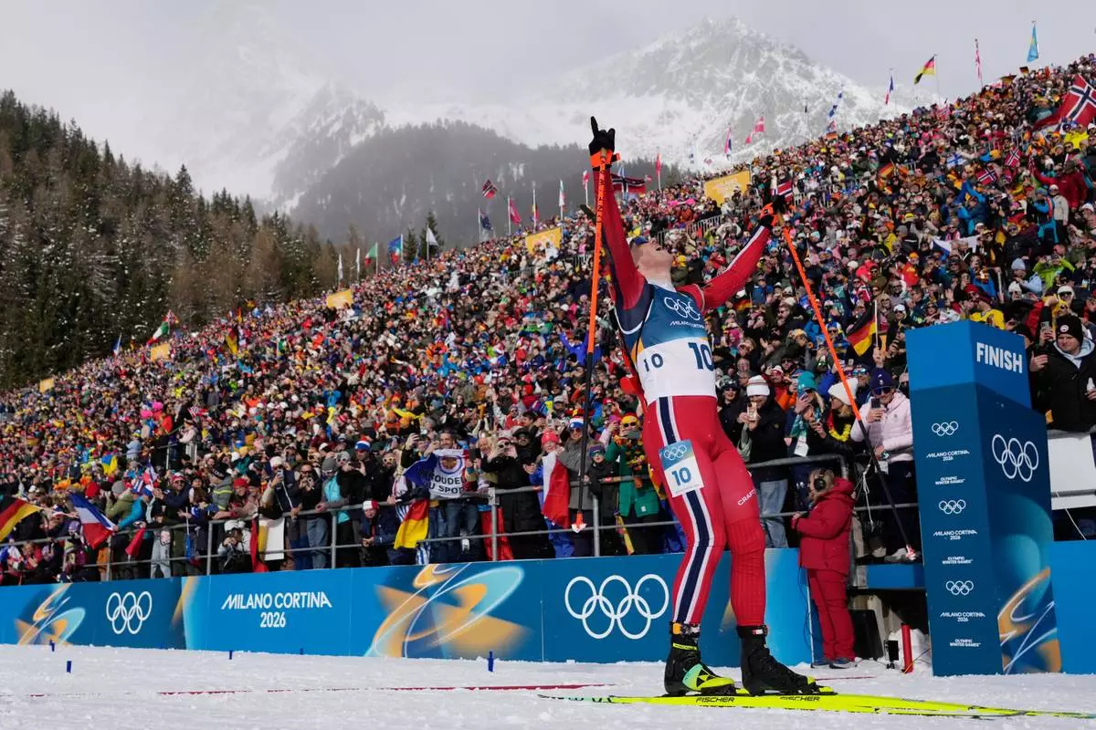 Johannes Dale-Skjevdal, of Norway, crosses the finish line to win gold in the men's 15-kilometer mass start biathlon race at the 2026 Winter Olympics in Anterselva, Italy, Friday, Feb. 20, 2026. (AP Photo/David J. Phillip)