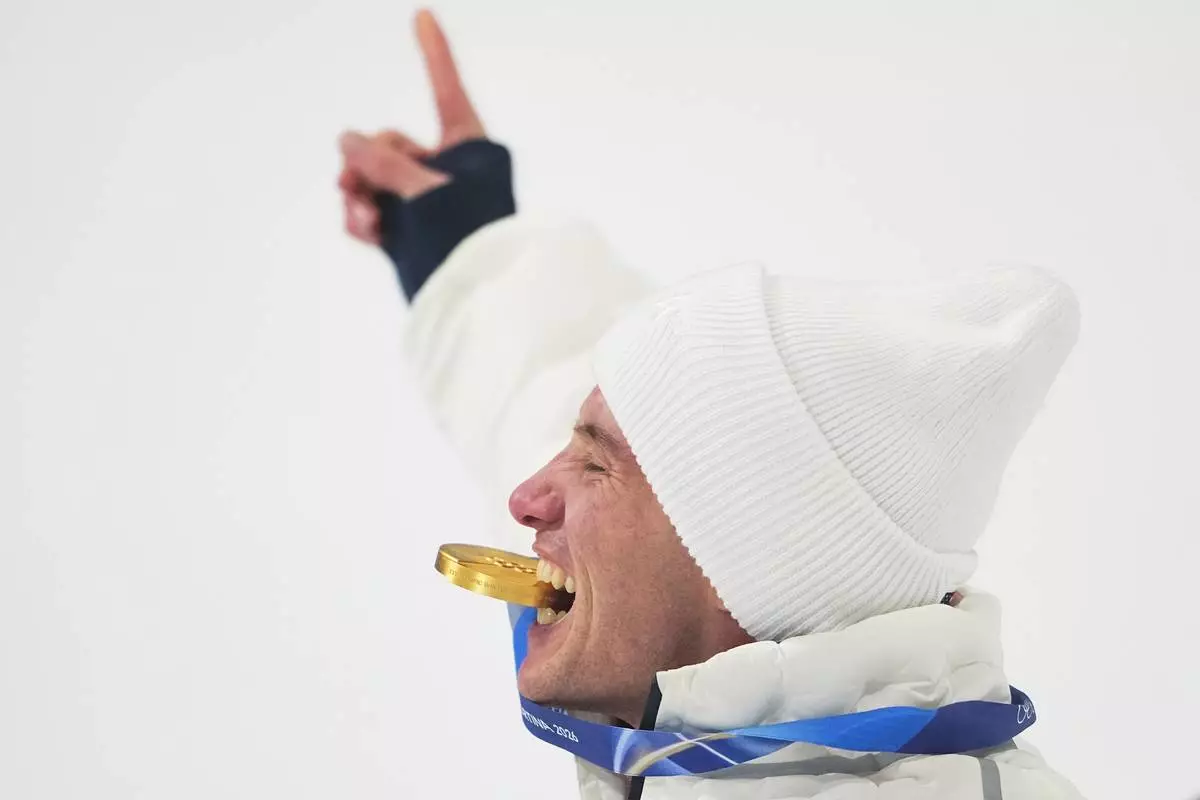 Gold medalist United States' Alex Ferreira bites his medal as he celebrates his win after the men's freestyle skiing halfpipe finals at the 2026 Winter Olympics, in Livigno, Italy, Friday, Feb. 20, 2026. (AP Photo/Lindsey Wasson)
