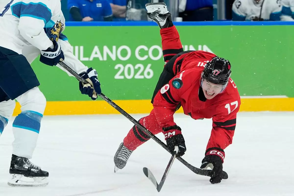 Finland's Esa Lindell (23) challenges for the puck with Canada's Macklin Celebrini (17) during a men's ice hockey semifinal game between Canada and Finland at the 2026 Winter Olympics, in Milan, Italy, Friday, Feb. 20, 2026. (AP Photo/Petr David Josek)