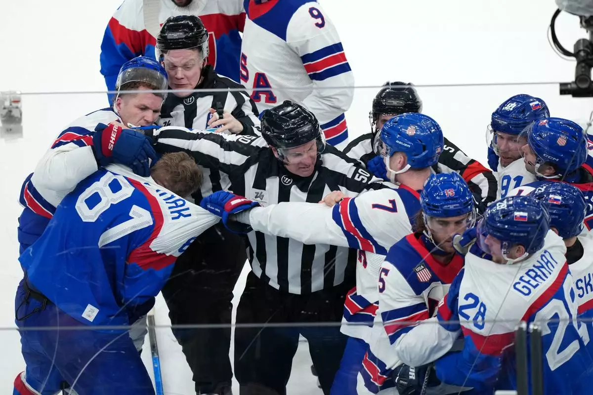 Linesperson Scott Cherrey (50) tries to stop a fight involving United States' Matthew Tkachuk, far left, Slovakia's Erik Cernak (81) and United States' Brady Tkachuk (7) during the third period of a men's ice hockey semifinal game at the 2026 Winter Olympics in Milan, Italy, Friday, Feb. 20, 2026. (AP Photo/Carolyn Kaster)