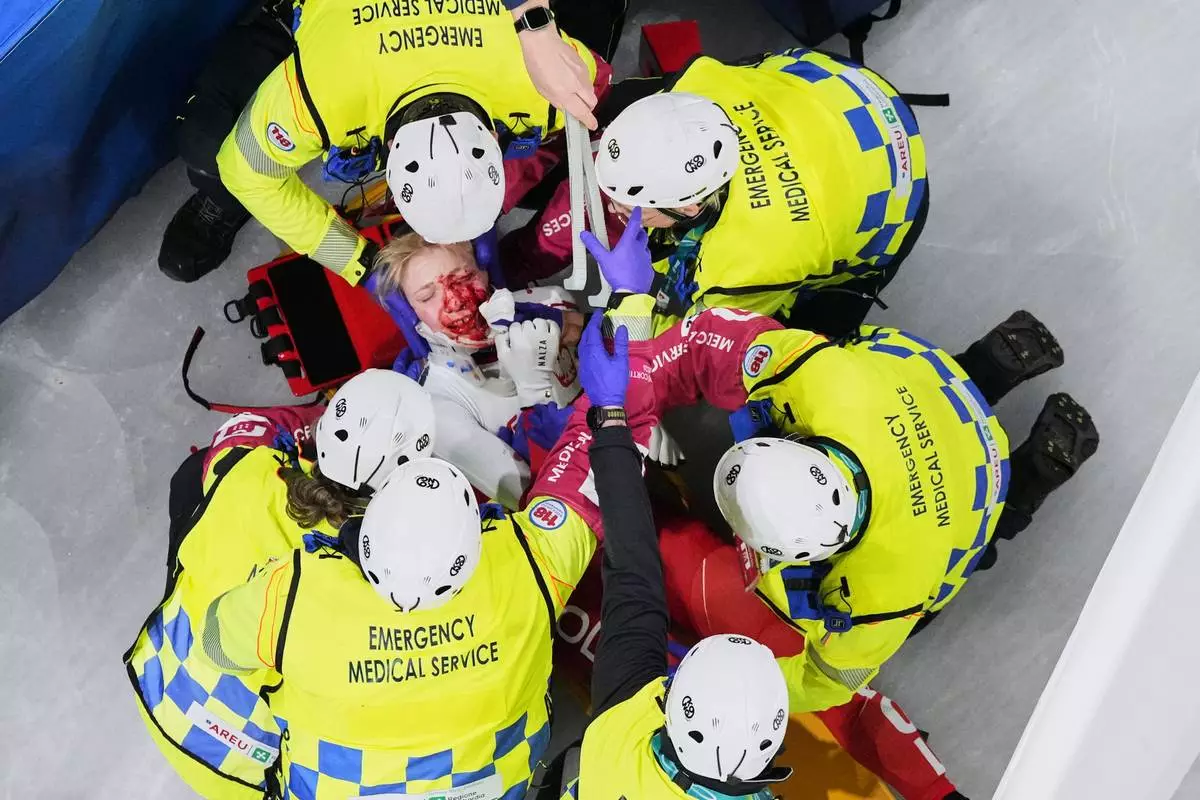Kamila Sellier of Poland is assisted by the emergency medical service team after an injury due to a fall during a short track speed skating women's 1500 meters quarterfinal at the 2026 Winter Olympics, in Milan, Italy, Friday, Feb. 20, 2026. (AP Photo/Bernat Armangue)