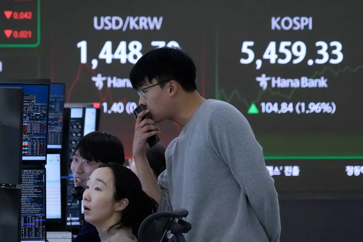 Currency traders watch monitors near a screen showing the Korea Composite Stock Price Index (KOSPI), right, and the foreign exchange rate between U.S. dollar and South Korean won at the foreign exchange dealing room of the Hana Bank headquarters in Seoul, South Korea, Thursday, Feb. 12, 2026. (AP Photo/Ahn Young-joon)