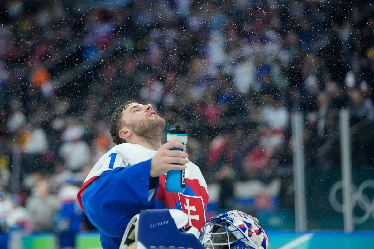 Slovakia's Samuel Hlavaj sprays water during a men's ice hockey quarterfinal game between Slovakia and Germany at the 2026 Winter Olympics, in Milan, Italy, Wednesday, Feb. 18, 2026. (AP Photo/Petr David Josek)