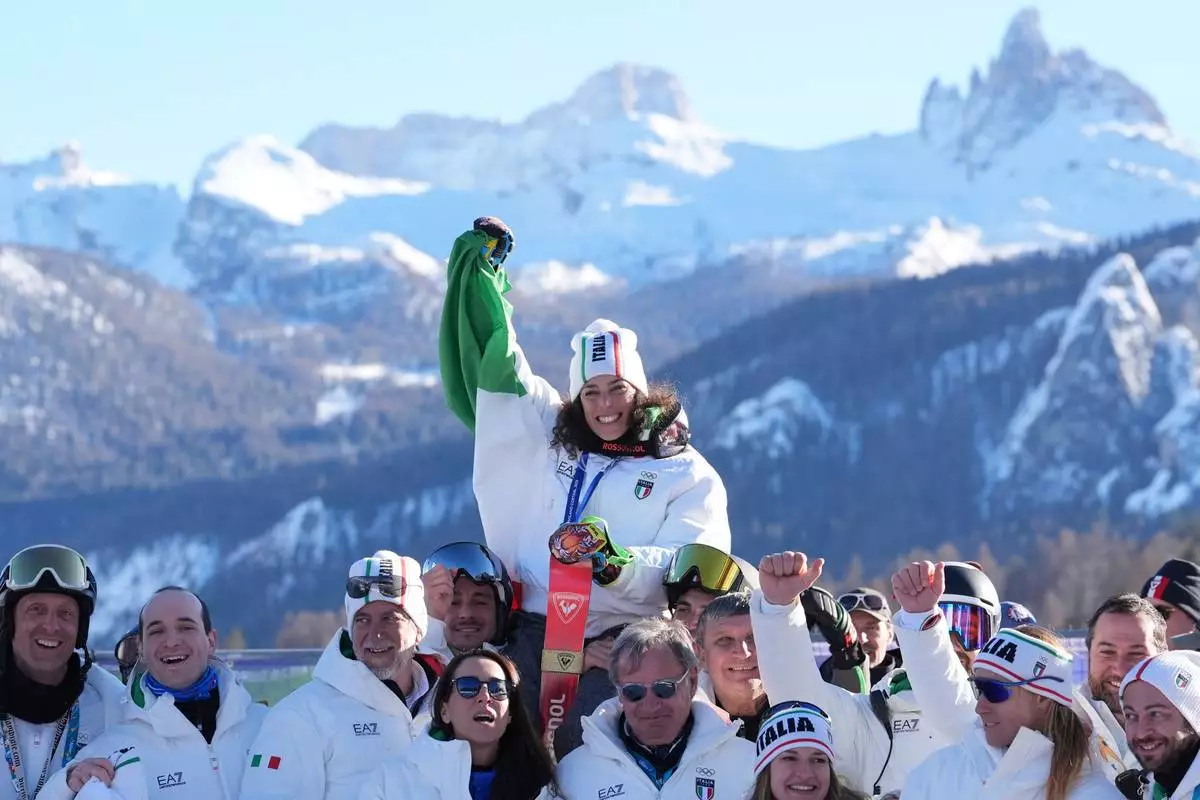 Italy's Federica Brignone, center, celebrates with members of the Italian team after winning the gold medal in an alpine ski, women's giant slalom race, at the 2026 Winter Olympics, in Cortina d'Ampezzo, Italy, Sunday, Feb. 15, 2026. (AP Photo/Jacquelyn Martin)
