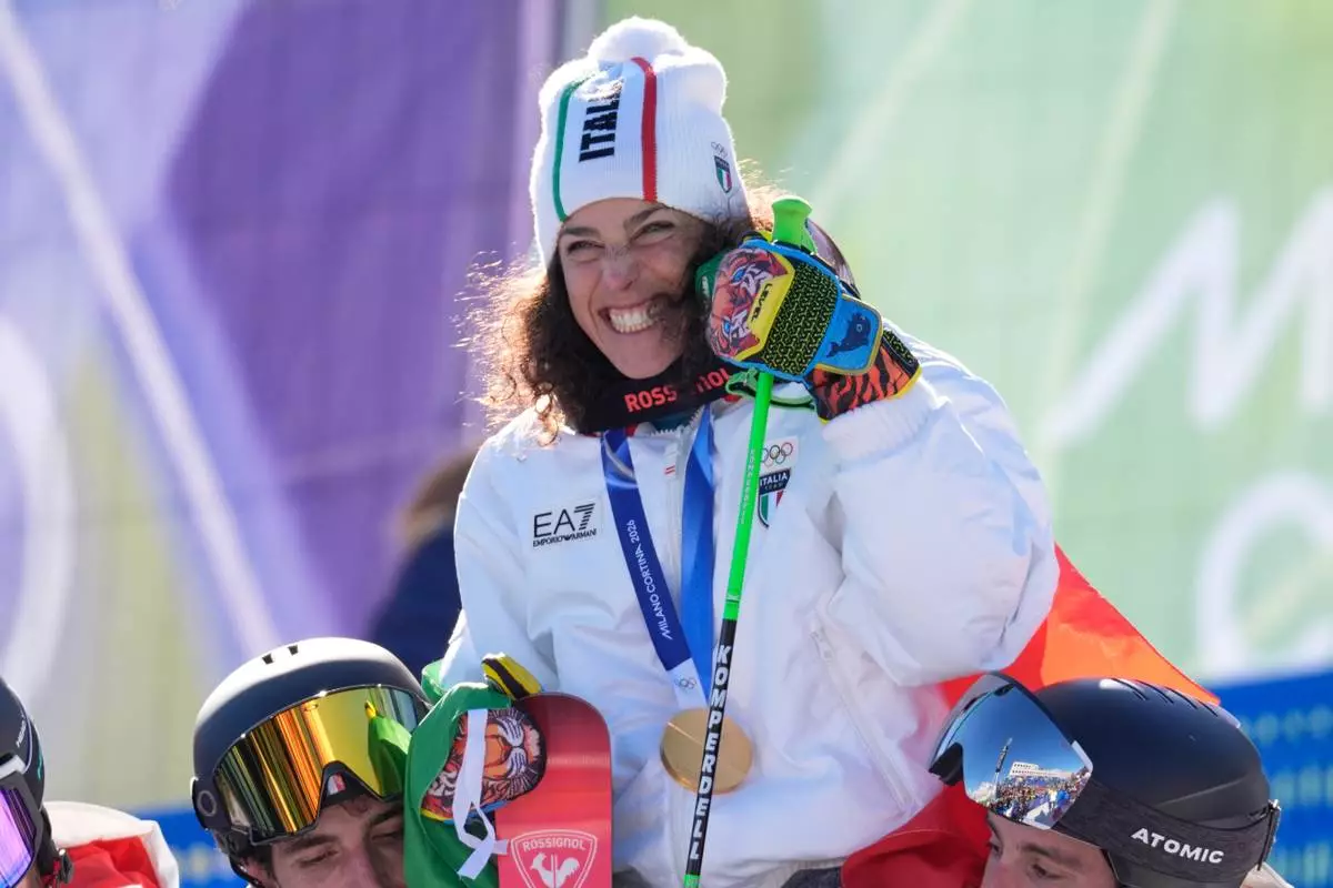Italy's Federica Brignone shows the gold medal of an alpine ski, women's giant slalom race, as she celebrates with teammates at the 2026 Winter Olympics, in Cortina d'Ampezzo, Italy, Sunday, Feb. 15, 2026. (AP Photo/Robert F. Bukaty)