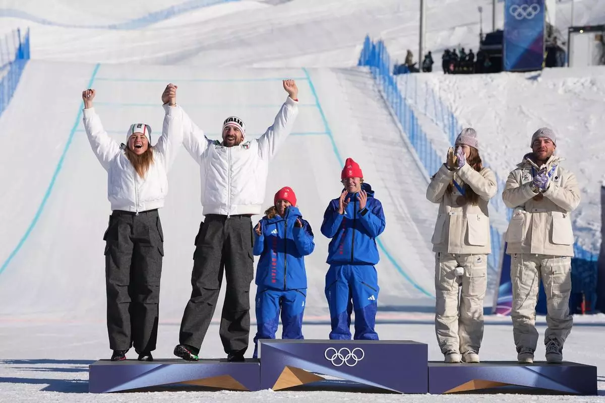 From left, silver medalists Italy's Michela Moioli and Lorenzo Sommariva, gold medalists Britain's Charlotte Bankes and Huw Nightingale, and bronze medalists France's Lea Casta and Loan Bozzolo celebrate after the mixed team snowboard cross finals at the 2026 Winter Olympics, in Livigno, Italy, Sunday, Feb. 15, 2026. (AP Photo/Lindsey Wasson)