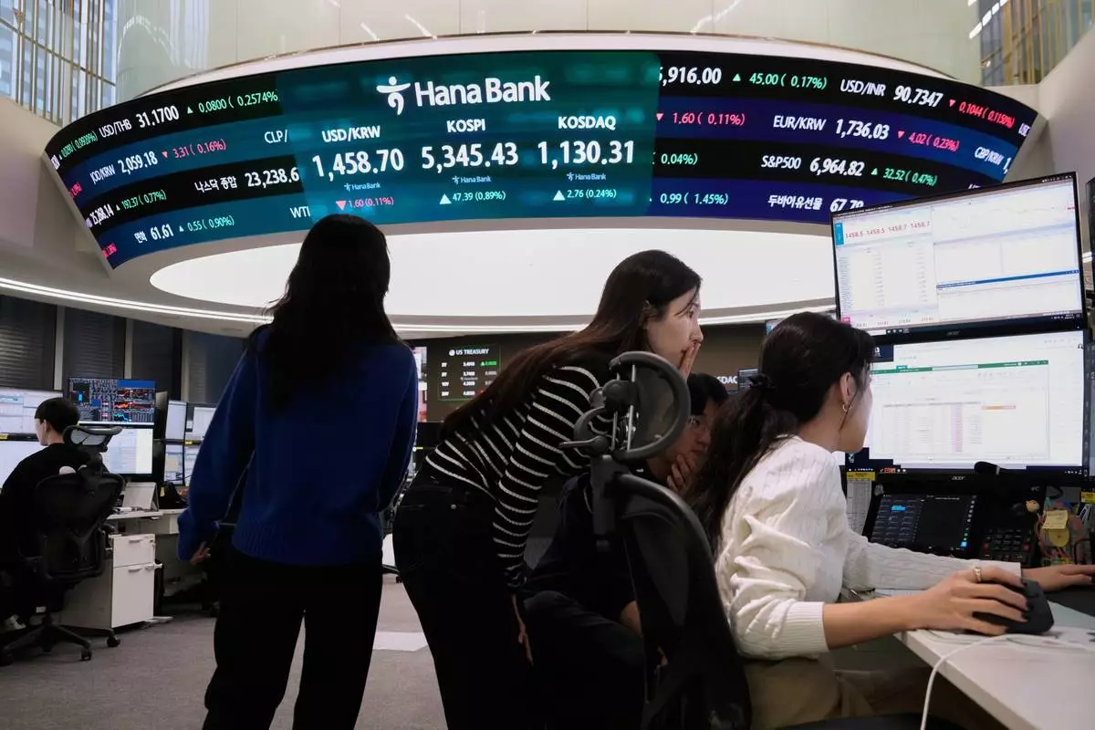 Currency traders watch monitors near a screen showing the Korea Composite Stock Price Index (KOSPI), top center, and the foreign exchange rate between U.S. dollar and South Korean won, top center left, at the foreign exchange dealing room of the Hana Bank headquarters in Seoul, South Korea, Tuesday, Feb. 10, 2026. (AP Photo/Ahn Young-joon)