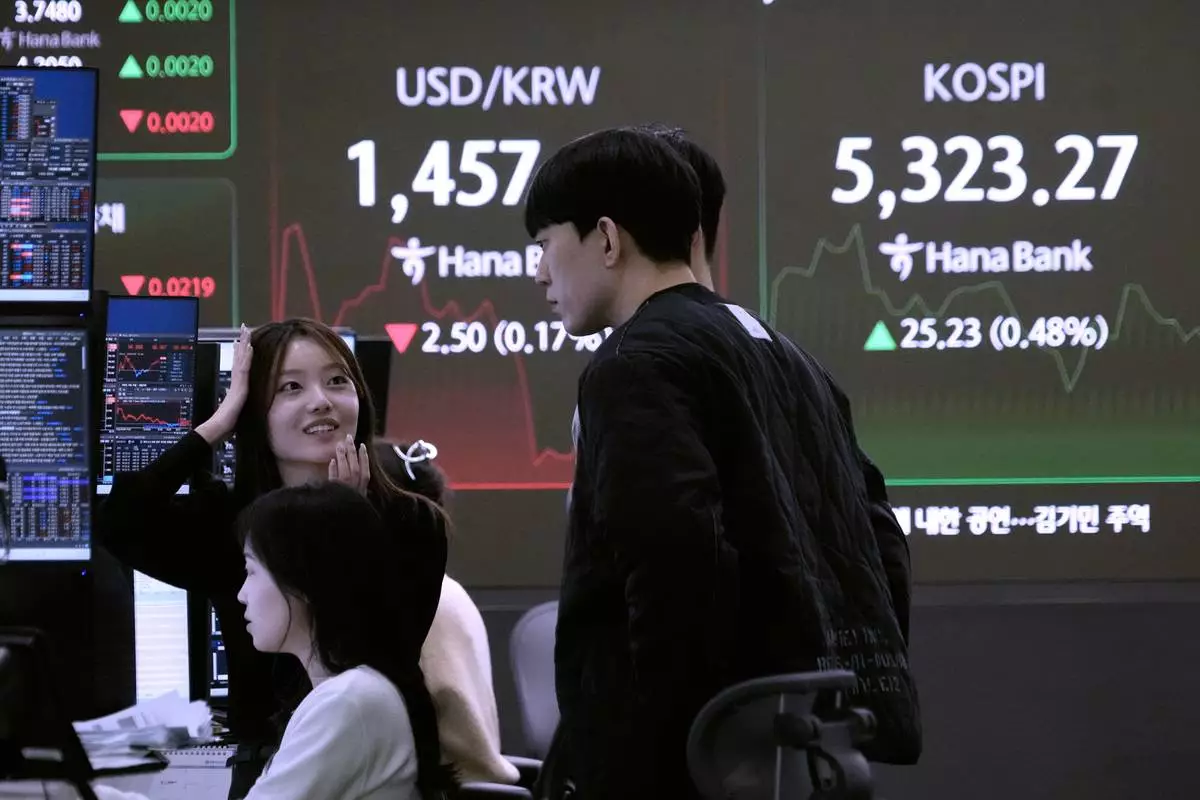 Currency traders work near a screen showing the Korea Composite Stock Price Index (KOSPI), top right, and the foreign exchange rate between U.S. dollar and South Korean won at the foreign exchange dealing room of the Hana Bank headquarters in Seoul, South Korea, Tuesday, Feb. 10, 2026. (AP Photo/Ahn Young-joon)