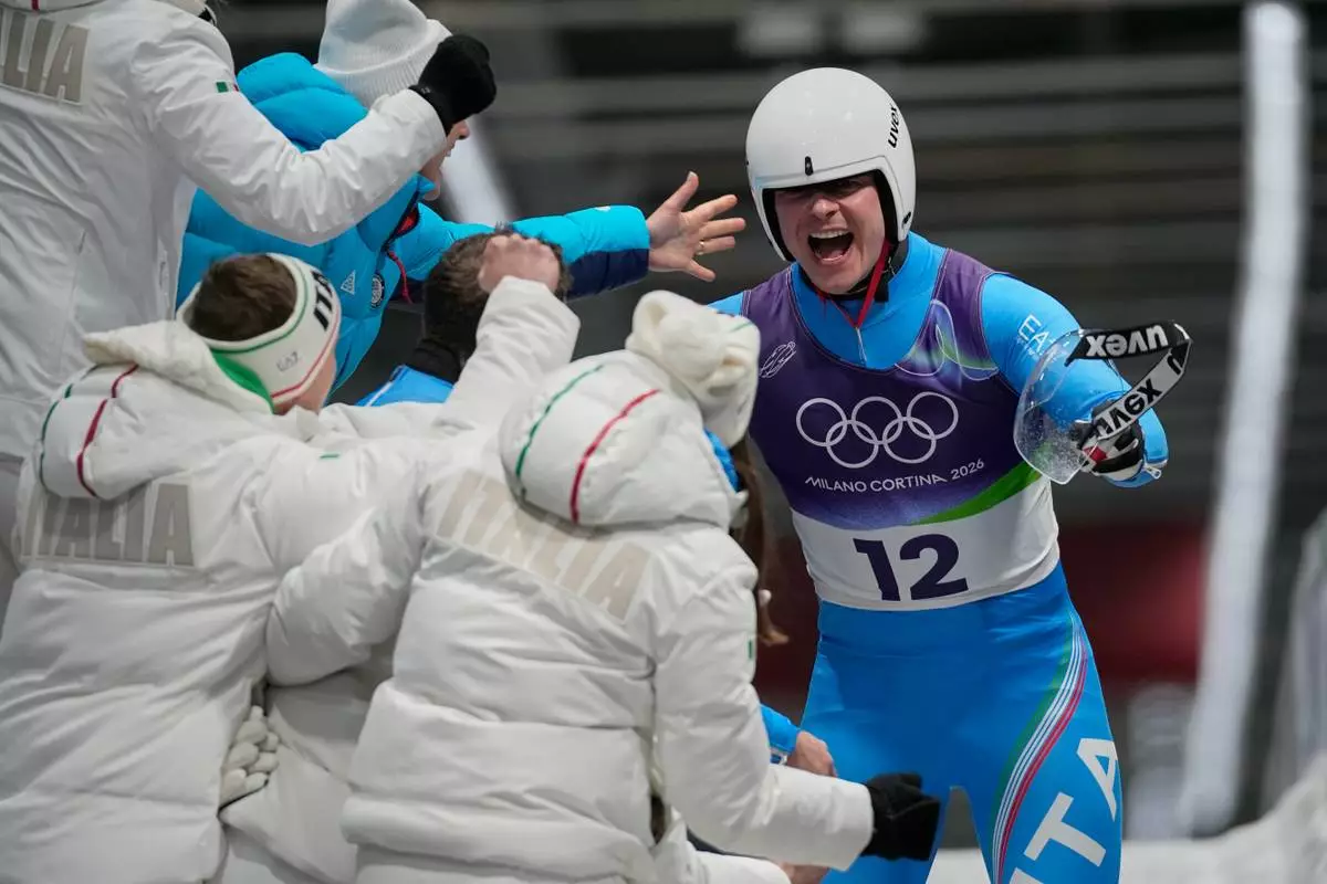 Italy's Dominik Fischnaller, right, celebrates winning the bronze medal as he arrives at the finish during a men's single luge run at the 2026 Winter Olympics, in Cortina d'Ampezzo, Italy, Sunday, Feb. 8, 2026. (AP Photo/Aijaz Rahi)