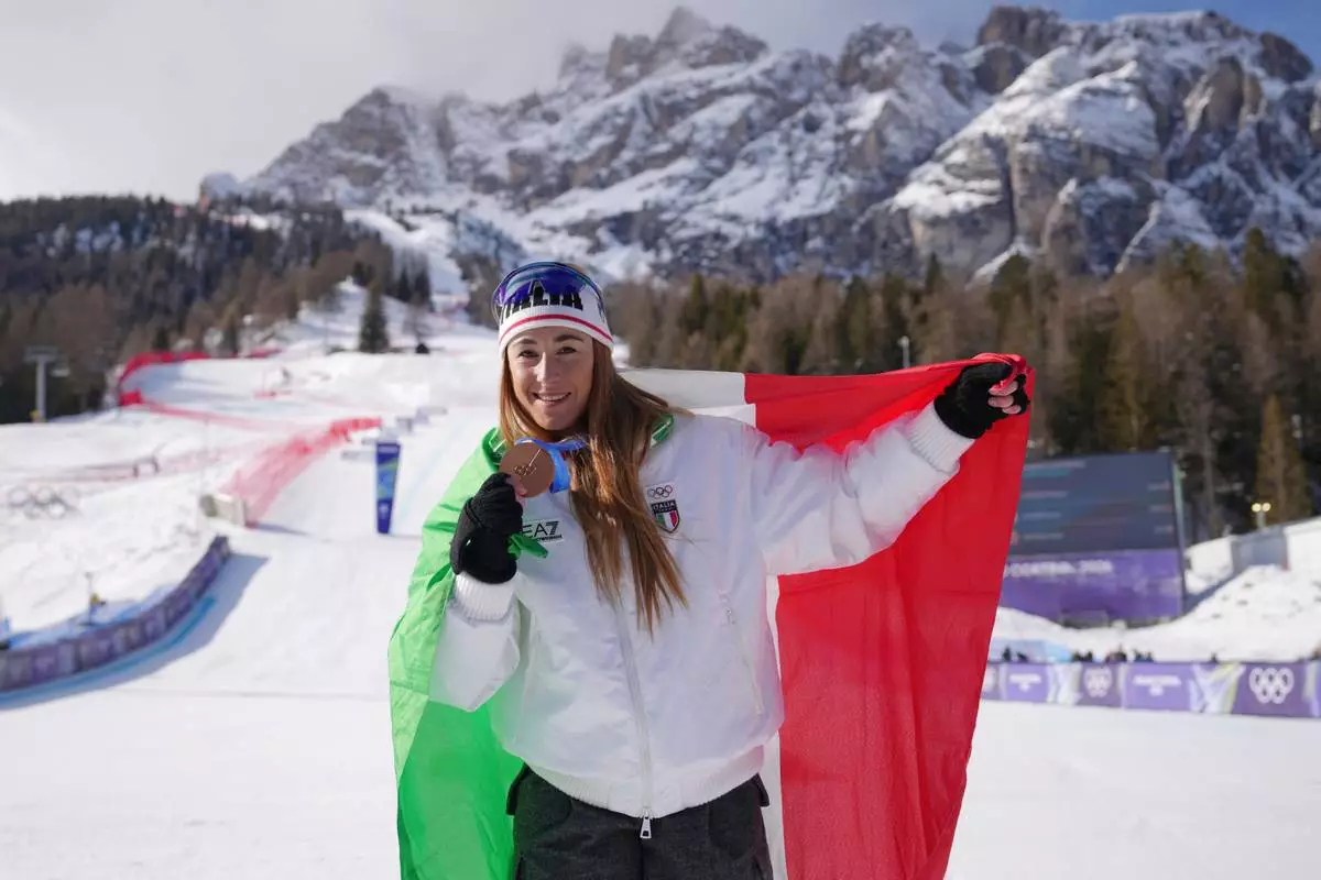 Italy's Sofia Goggia shows her bronze medal for an alpine ski women's downhill race, at the 2026 Winter Olympics, in Cortina d'Ampezzo, Italy, Sunday, Feb. 8, 2026. (AP Photo/Andy Wong)