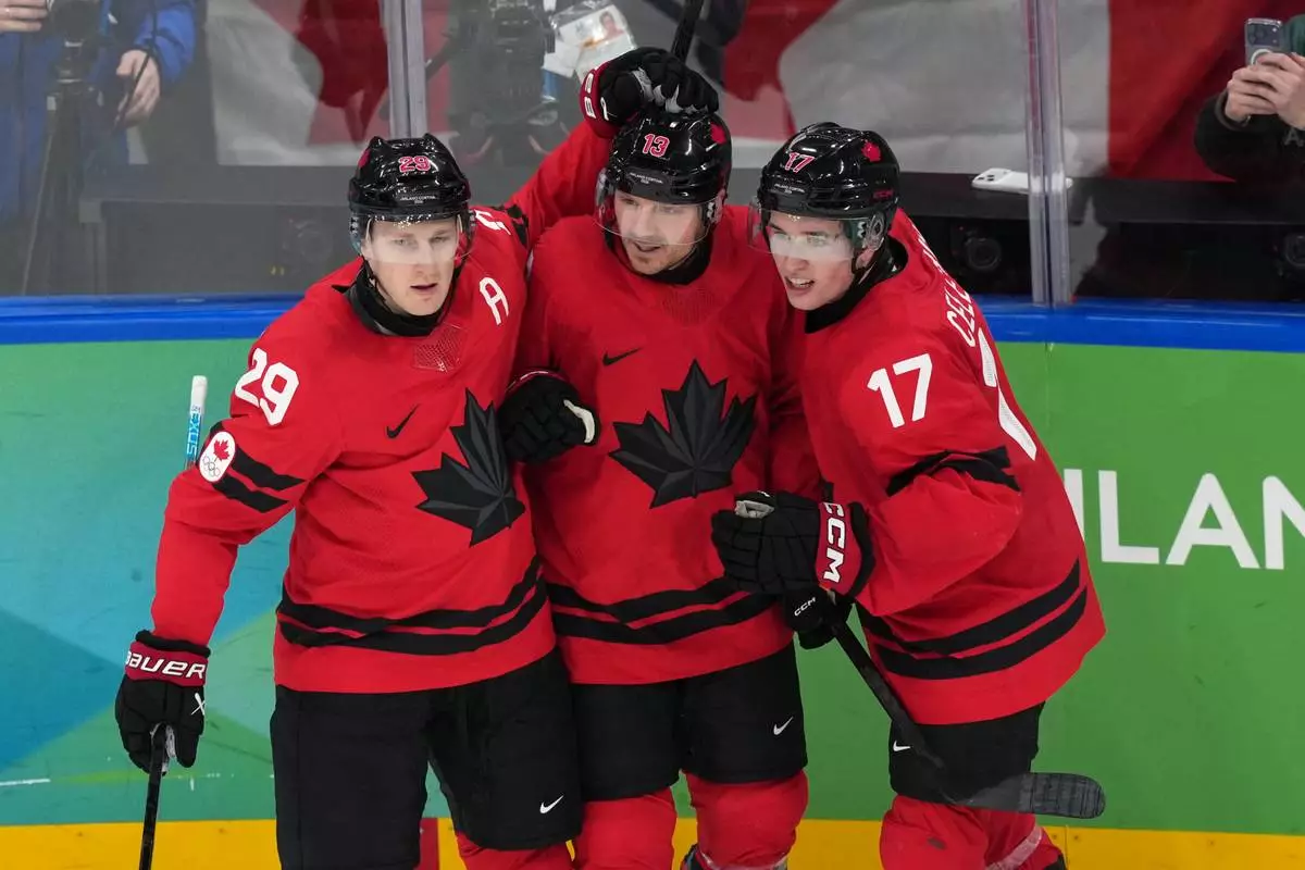 Canada's Sam Reinhart (13) celebrates with Nathan MacKinnon (29) and Macklin Celebrini (17) after Reinhart scored a goal against Finland during the second period of a men's ice hockey semifinal game at the 2026 Winter Olympics in Milan, Italy, Friday, Feb. 20, 2026. (AP Photo/Carolyn Kaster)