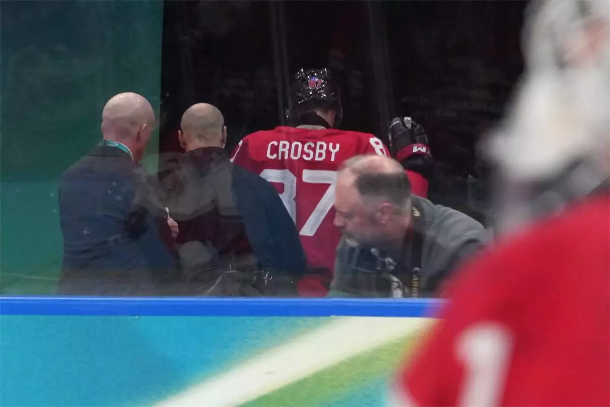 Canada's Sidney Crosby (87) is helped as he leaves the bench after being checked against the boards during the second period of a men's ice hockey quarterfinal game between Canada and Czechia at the 2026 Winter Olympics, in Milan, Italy, Wednesday, Feb. 18, 2026. (AP Photo/Carolyn Kaster)
