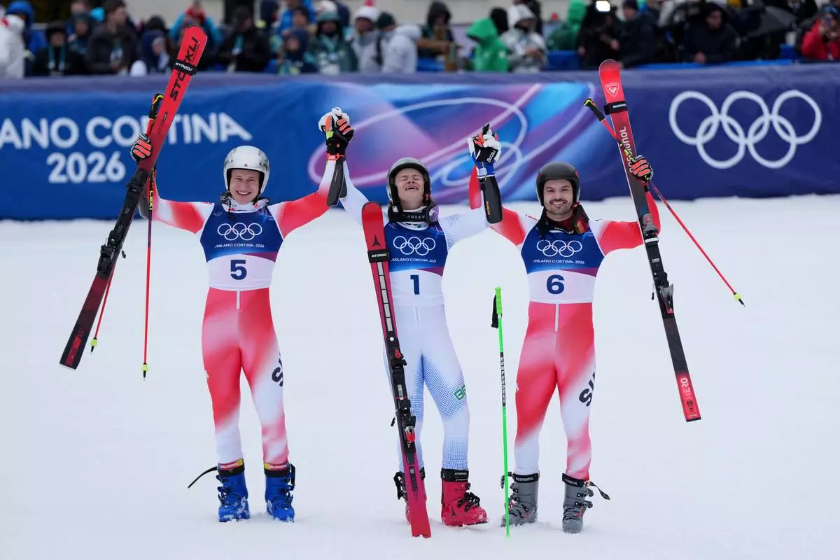 Brazil's Lucas Pinheiro Braathen, center, winner of a gold medal in an alpine ski, men's giant slalom race, celebrates with silver medalist Switzerland's Marco Odermatt, left, and bronze medalist Switzerland's Loic Meillard, at the 2026 Winter Olympics, in Bormio, Italy, Saturday, Feb. 14, 2026. (AP Photo/Julia Demaree Nikhinson)