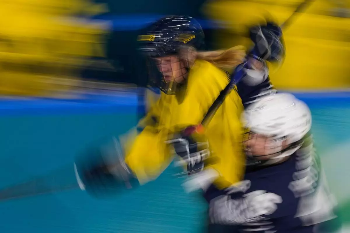 Sweden's Thea Johansson, left, challenges France's Clara Rozier during a preliminary round match of women's ice hockey between France and Sweden at the 2026 Winter Olympics, in Milan, Italy, Sunday, Feb. 8, 2026. (AP Photo/Petr David Josek)