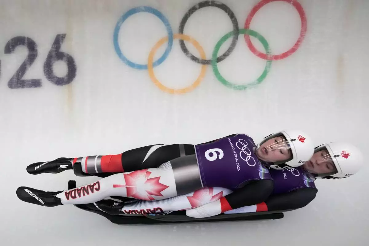 Canada's Beattie Podulsky, left, and Kailey Allan, right, slide down the track during a women's doubles luge training session at the 2026 Winter Olympics, in Cortina d'Ampezzo, Italy, Sunday, Feb. 8, 2026. (AP Photo/Aijaz Rahi)