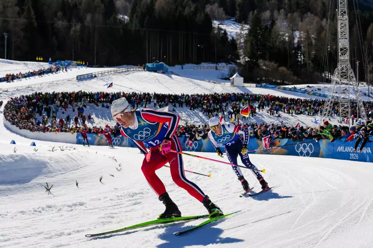 Johannes Hoesflot Klaebo, of Norway, and Gus Schumacher, of the United States, right, compete in the cross-country skiing men's team sprint free at the 2026 Winter Olympics, in Tesero, Italy, Wednesday, Feb. 18, 2026. (AP Photo/Evgeniy Maloletka)