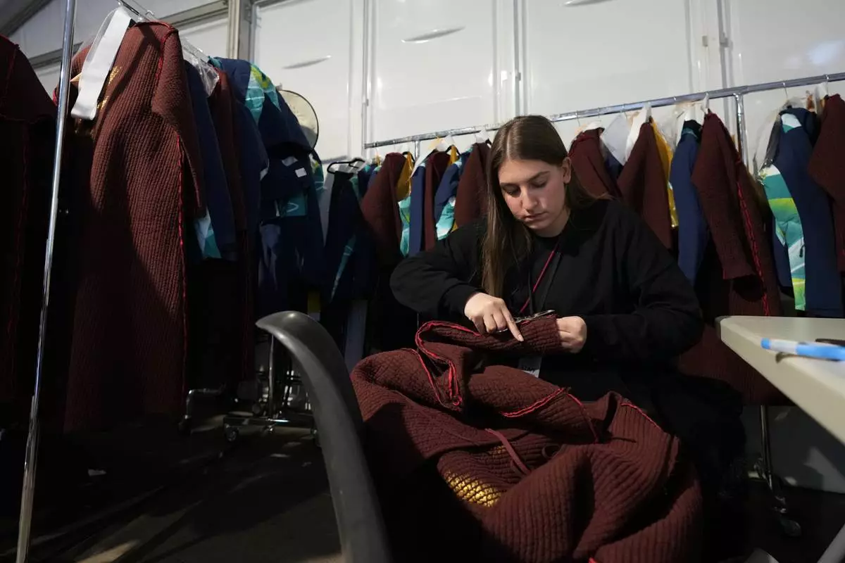 Dressmaker Giulia Ciccarelli works in a dress room outside the Arena ahead of the closing ceremony at the 2026 Winter Olympics, in Verona, Italy, Tuesday, Feb. 17, 2026. (AP Photo/Antonio Calanni)