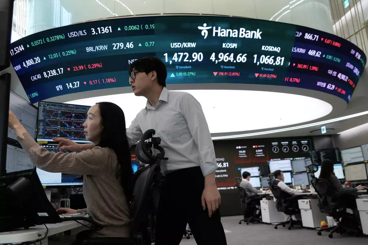 Currency traders watch monitors near a screen showing the Korea Composite Stock Price Index (KOSPI), top center, and the foreign exchange rate between U.S. dollar and South Korean won, top center left, at the foreign exchange dealing room of the Hana Bank headquarters in Seoul, South Korea, Friday, Feb. 6, 2026. (AP Photo/Ahn Young-joon)