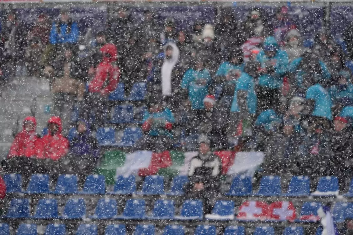 Spectators are seen through a snowfall at the finish area of an alpine ski, men's slalom race, at the 2026 Winter Olympics, in Bormio, Italy, Monday, Feb. 16, 2026. (AP Photo/Rebecca Blackwell)