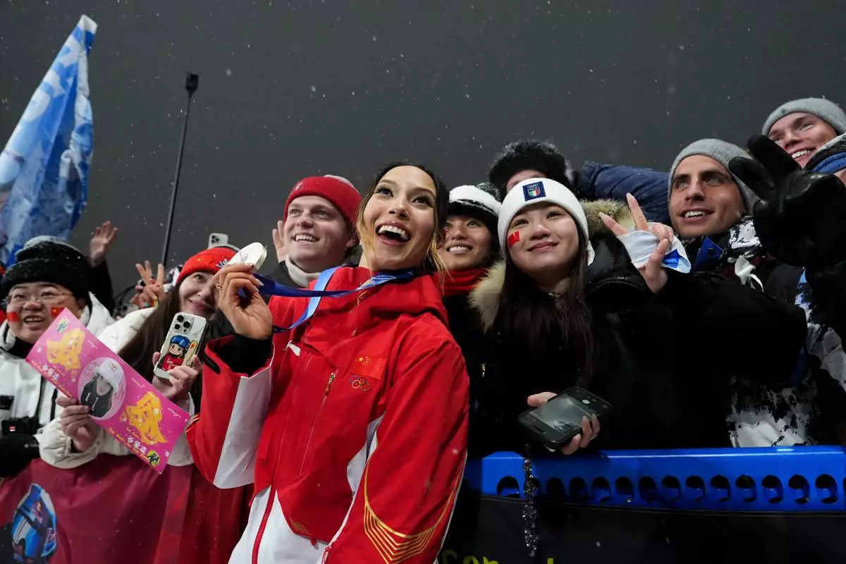 Silver medalist China's Eileen Gu celebrates with fans after the women's freestyle skiing big air finals at the 2026 Winter Olympics, in Livigno, Italy, Monday, Feb. 16, 2026. (AP Photo/Gregory Bull)