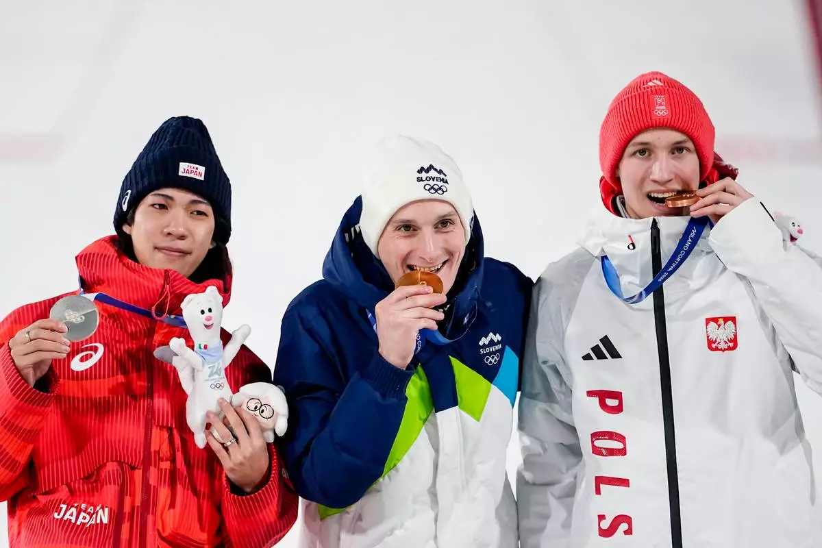 Silver medalist Ren Nikaido, of Japan, gold medalist Domen Prevc, of Slovenia, and bronze medalist Kacper Tomasiak, of Poland, pose on the podium at the end of the ski jumping men's large hill individual at the 2026 Winter Olympics, in Predazzo, Italy, Saturday, Feb. 14, 2026.. (AP Photo/Matthias Schrader)