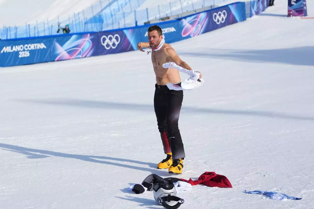 Austria's Benjamin Karl takes off his shirt as he celebrates winning the gold medal after the men's snowboarding parallel giant slalom finals at the 2026 Winter Olympics, in Livigno, Italy, Sunday, Feb. 8, 2026. (AP Photo/Lindsey Wasson)