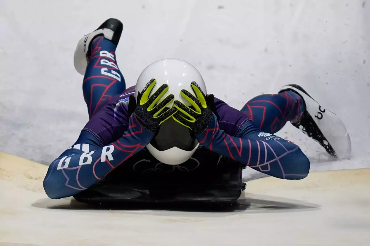 Britain's gold medalist Matt Weston celebrates as he arrives at the finish during a men's skeleton run at the 2026 Winter Olympics, in Cortina d'Ampezzo, Italy, Friday, Feb. 13, 2026. (AP Photo/Aijaz Rahi)