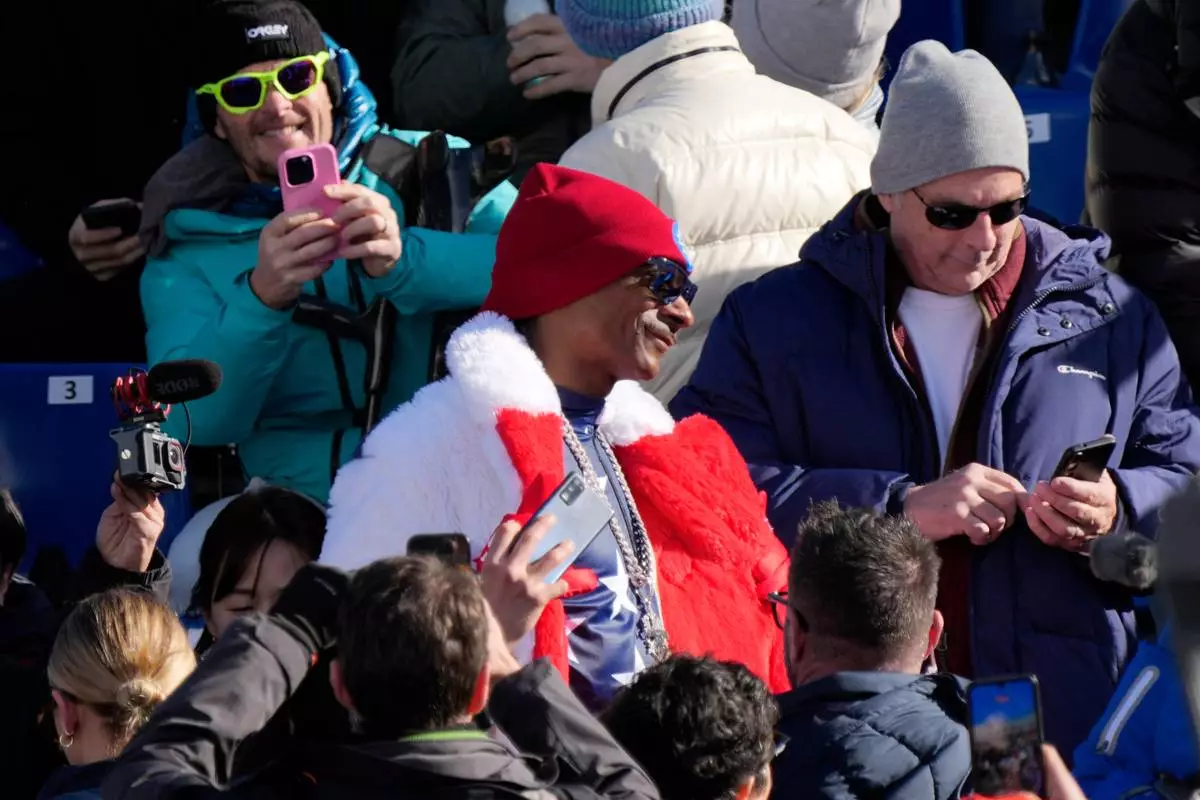 Snoop Dogg in the stands at the finish area of an alpine ski women's downhill race, at the 2026 Winter Olympics, in Cortina d'Ampezzo, Italy, Sunday, Feb. 8, 2026. (AP Photo/Andy Wong)