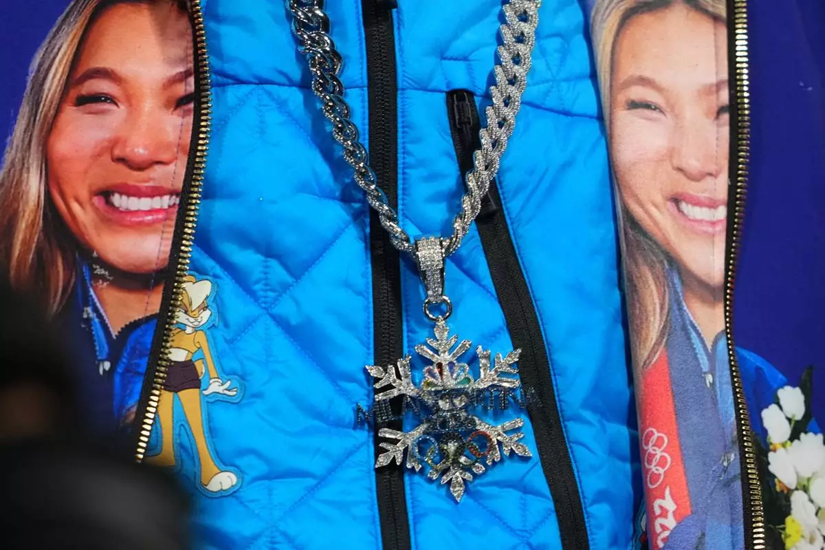 Snoop Dogg wears a chain and jacket displaying United States' Chloe Kim during the women's snowboarding halfpipe finals at the 2026 Winter Olympics, in Livigno, Italy, Thursday, Feb. 12, 2026. (AP Photo/Lindsey Wasson)
