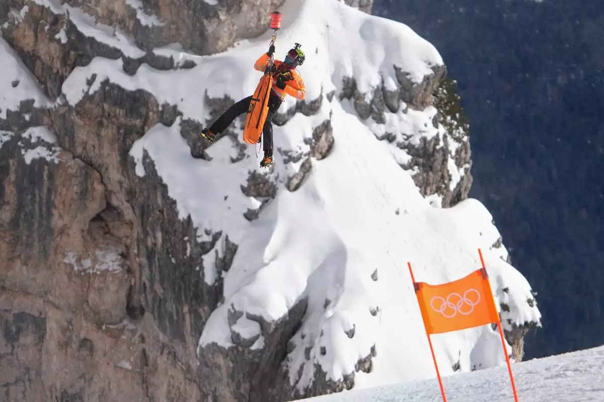 Rescue personnel is lowered from a helicopter to airlift United States' Lindsey Vonn after her crash during an alpine ski women's downhill race, at the 2026 Winter Olympics, in Cortina d'Ampezzo, Italy, Sunday, Feb. 8, 2026. (AP Photo/Jacquelyn Martin)