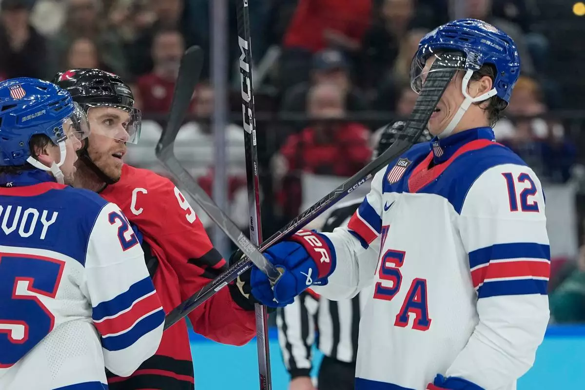United States' Matt Boldy (12) is hit in the face by the stick of Canada's Connor McDavid (97) during the first period of a men's ice hockey gold medal game between Canada and the United States at the 2026 Winter Olympics, in Milan, Italy, Sunday, Feb. 22, 2026. (AP Photo/Petr David Josek)