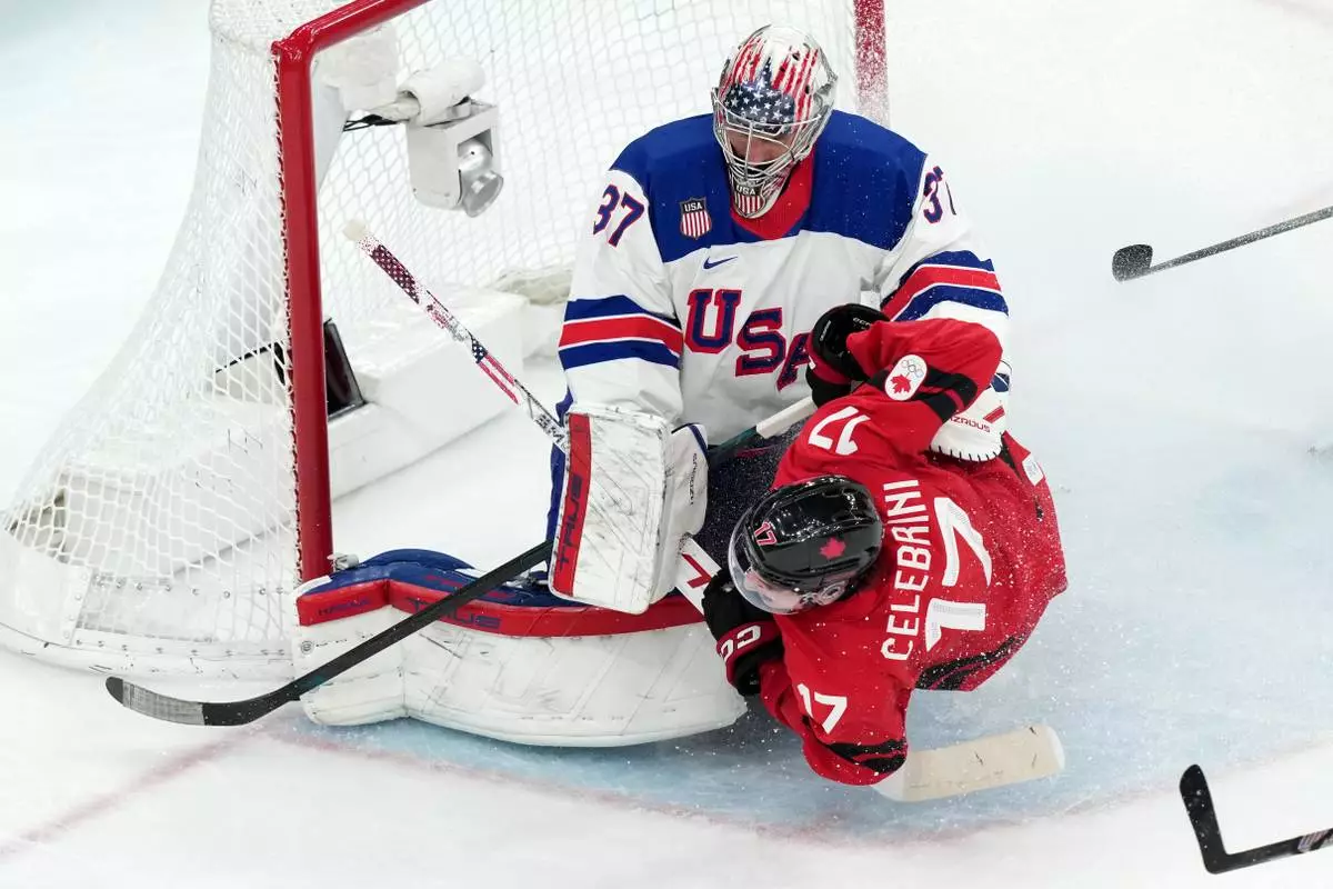 Canada's Macklin Celebrini (17) slides into United States goalkeeper Connor Hellebuyck (37) during the third period of the men's ice hockey gold medal game at the 2026 Winter Olympics in Milan, Italy, Sunday, Feb. 22, 2026. (AP Photo/Carolyn Kaster)