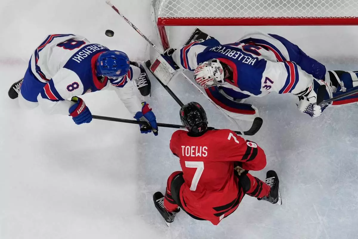 Canada's Devon Toews (7) challenges with United States' Zach Werenski (8) during a men's ice hockey gold medal game between Canada and the United States at the 2026 Winter Olympics, in Milan, Italy, Sunday, Feb. 22, 2026. (AP Photo/Petr David Josek)