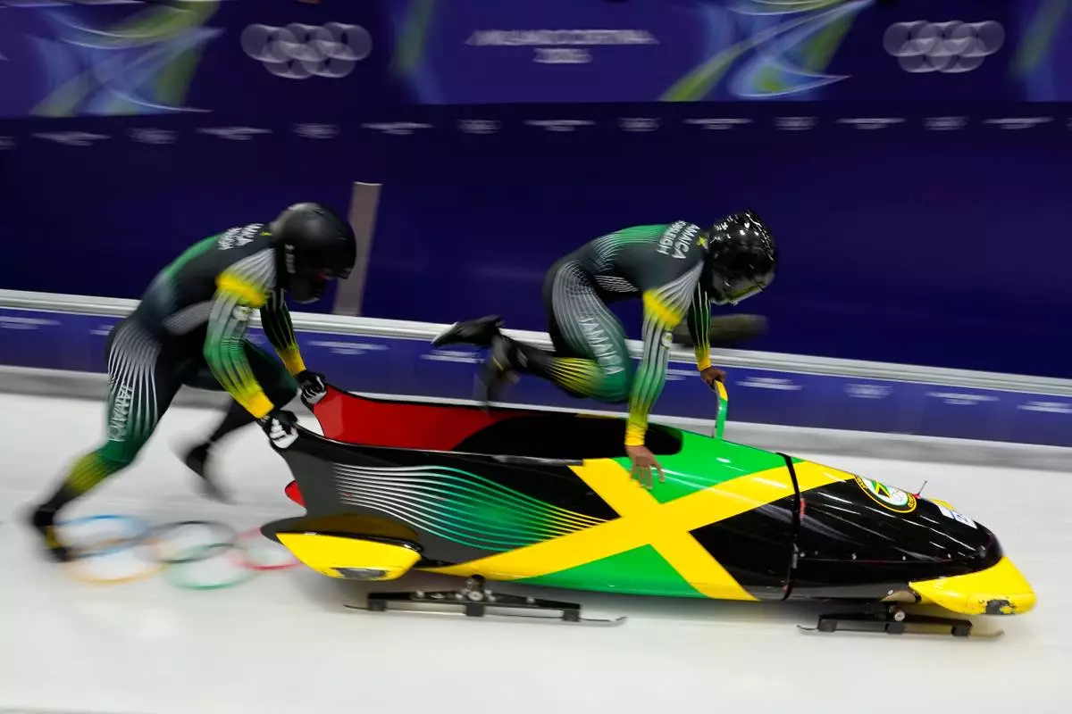 Jamaica's Shane Pitter, right, and Junior Harris start for a two man bobsled run at the 2026 Winter Olympics, in Cortina d'Ampezzo, Italy, Monday, Feb. 16, 2026. (AP Photo/Aijaz Rahi)