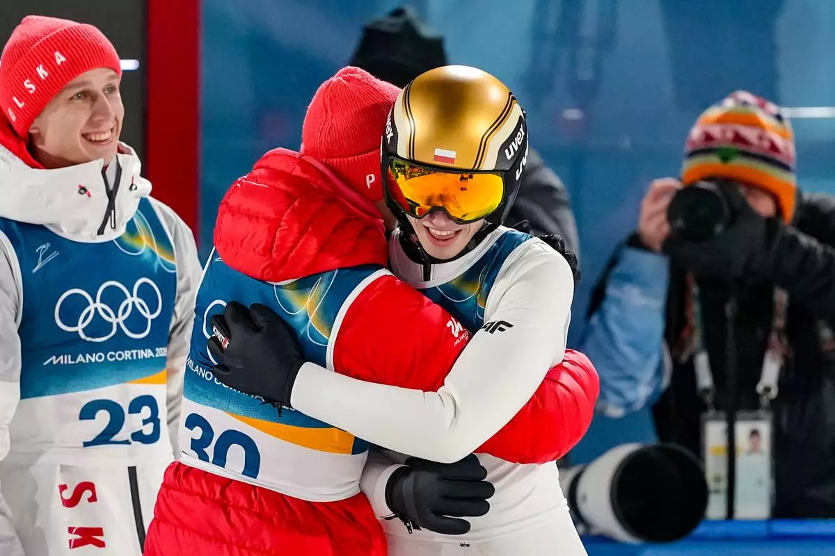 Kacper Tomasiak, of Poland, right, celebrates with teammates Kamil Stoch and Pawel Wasek, left, after his final round jump during the ski jumping men's normal hill individual at the 2026 Winter Olympics, in Predazzo, Italy, Monday, Feb. 9, 2026. (AP Photo/Matthias Schrader)
