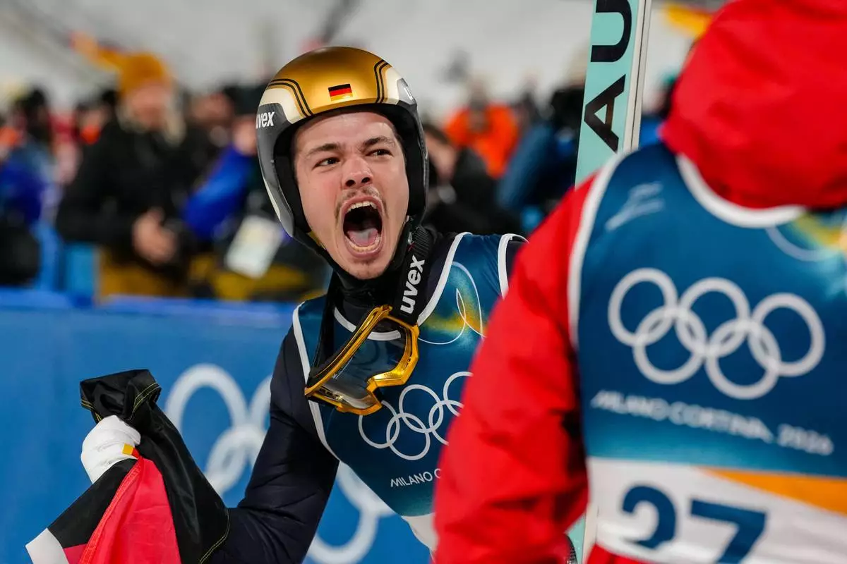 Philipp Raimund, of Germany, celebrates after winning the gold medal in the ski jumping men's normal hill individual at the 2026 Winter Olympics, in Predazzo, Italy, Monday, Feb. 9, 2026. (AP Photo/Evgeniy Maloletka)