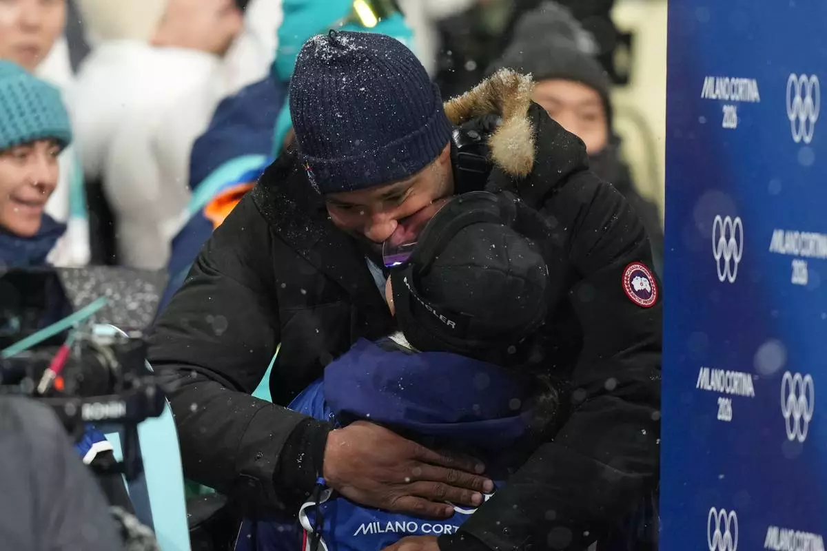 Cleveland Browns' Myles Garrett and United States' Chloe Kim kiss after Kim won the silver medal in the women's snowboarding halfpipe finals at the 2026 Winter Olympics, in Livigno, Italy, Thursday, Feb. 12, 2026. (AP Photo/Abbie Parr)