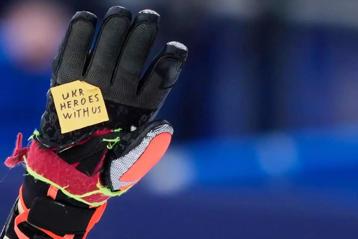 Ukraine's Dmytro Shepiuk holds a sticker reading "UKR heroes with us" at the finish area during a men's super-G race, at the 2026 Winter Olympics, in Bormio, Italy, Wednesday, Feb.11, 2026. (AP Photo/Julia Demaree Nikhinson)