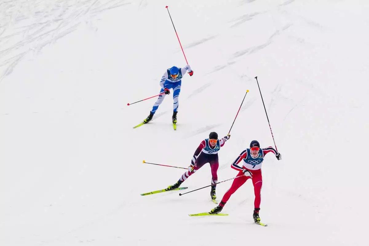 Jens Luraas Oftebro, of Norway, from right, Johannes Lamparter, of Austria and Eero Hirvonen, of Finland, approach the finish line in the Nordic Combined Individual Gundersen Normal Hill/10km competition at the 2026 Winter Olympics, in Tesero, Italy, Wednesday, Feb. 11, 2026. (AP Photo/Evgeniy Maloletka)