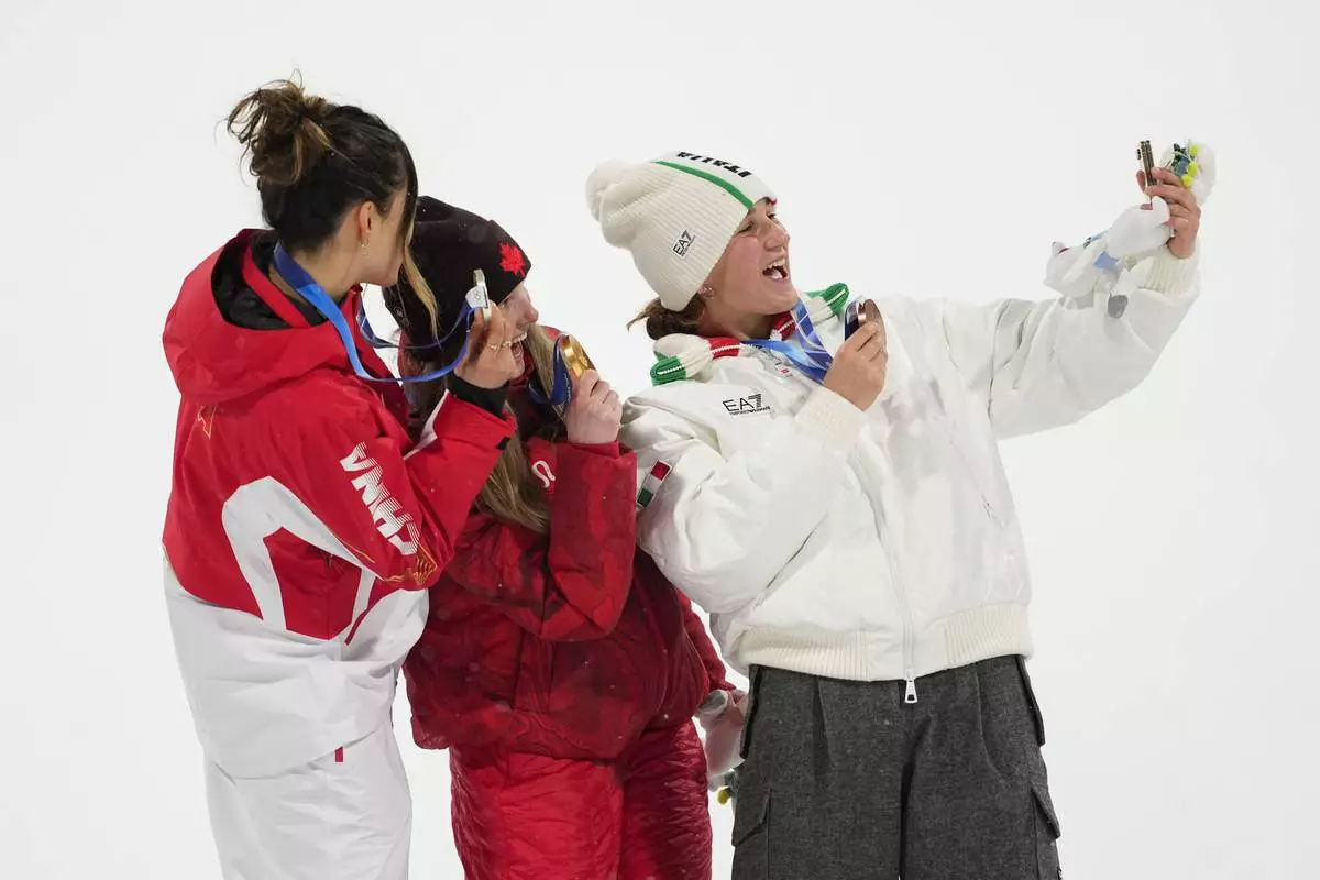 From left, silver medalist China's Eileen Gu, gold medalist Canada's Megan Oldham and bronze medalist Itay's Flora Tabanelli take a selfie after the women's freestyle skiing big air finals at the 2026 Winter Olympics, in Livigno, Italy, Monday, Feb. 16, 2026. (AP Photo/Lindsey Wasson)