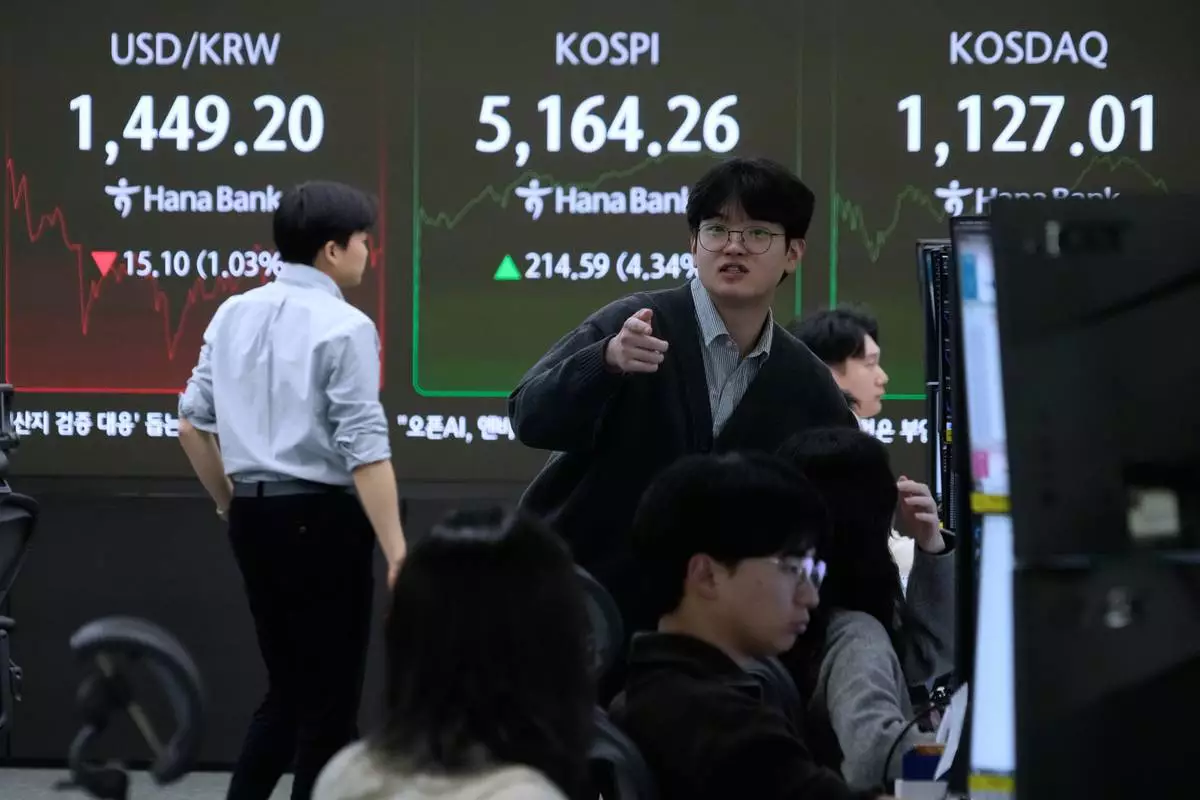 Currency traders work near a screen showing the Korea Composite Stock Price Index (KOSPI), top center, and the foreign exchange rate between U.S. dollar and South Korean won, top left, at the foreign exchange dealing room of the Hana Bank headquarters in Seoul, South Korea, Tuesday, Feb. 3, 2026. (AP Photo/Ahn Young-joon)