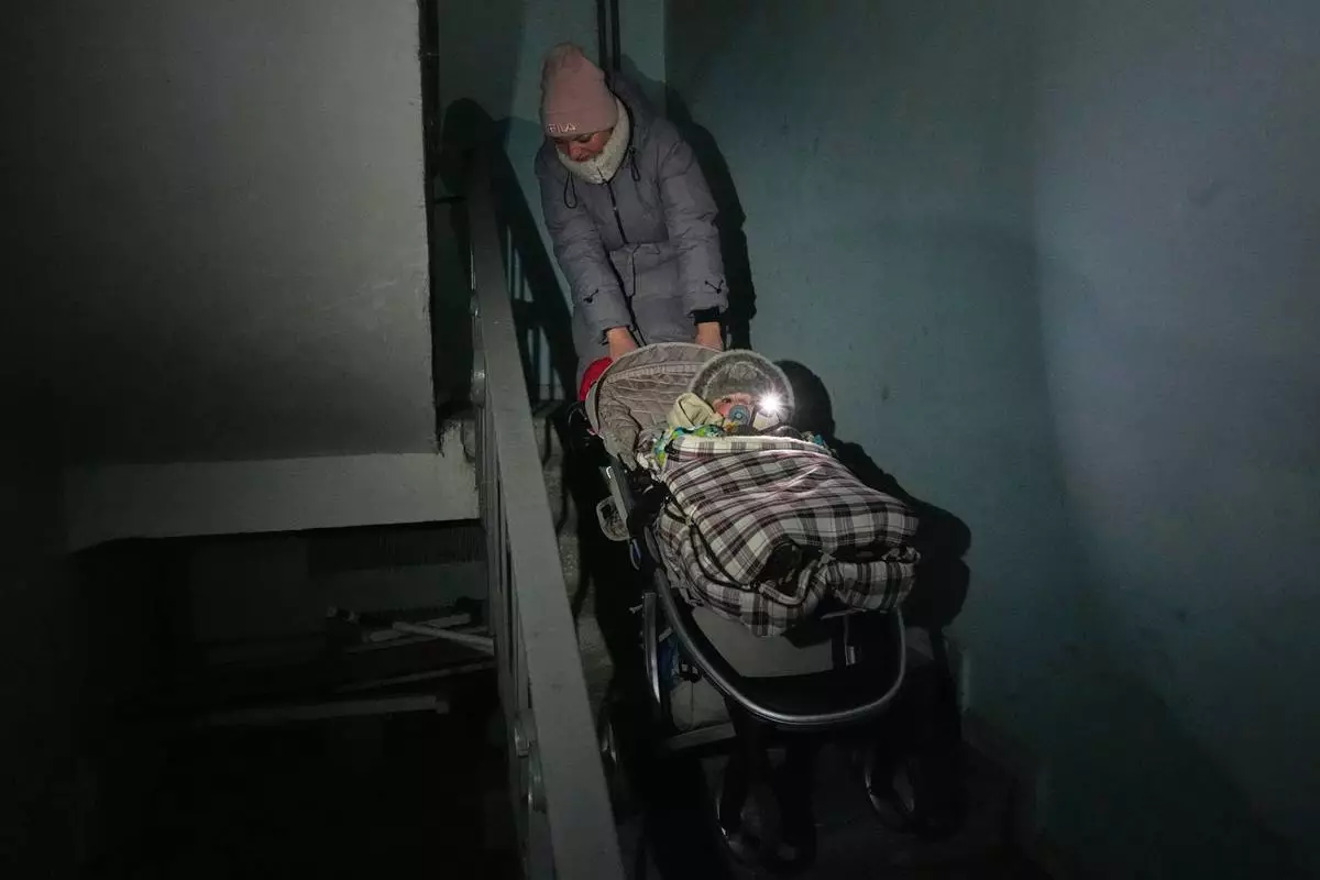 Yuliia Dolotova, 37, pulls her son in his stroller up the stairs in an apartment block during a power outage caused by Russia’s repeated air strikes on the country’s power grid, in Kyiv, Ukraine, Monday, Feb. 2, 2026. (AP Photo/Sergey Grits)