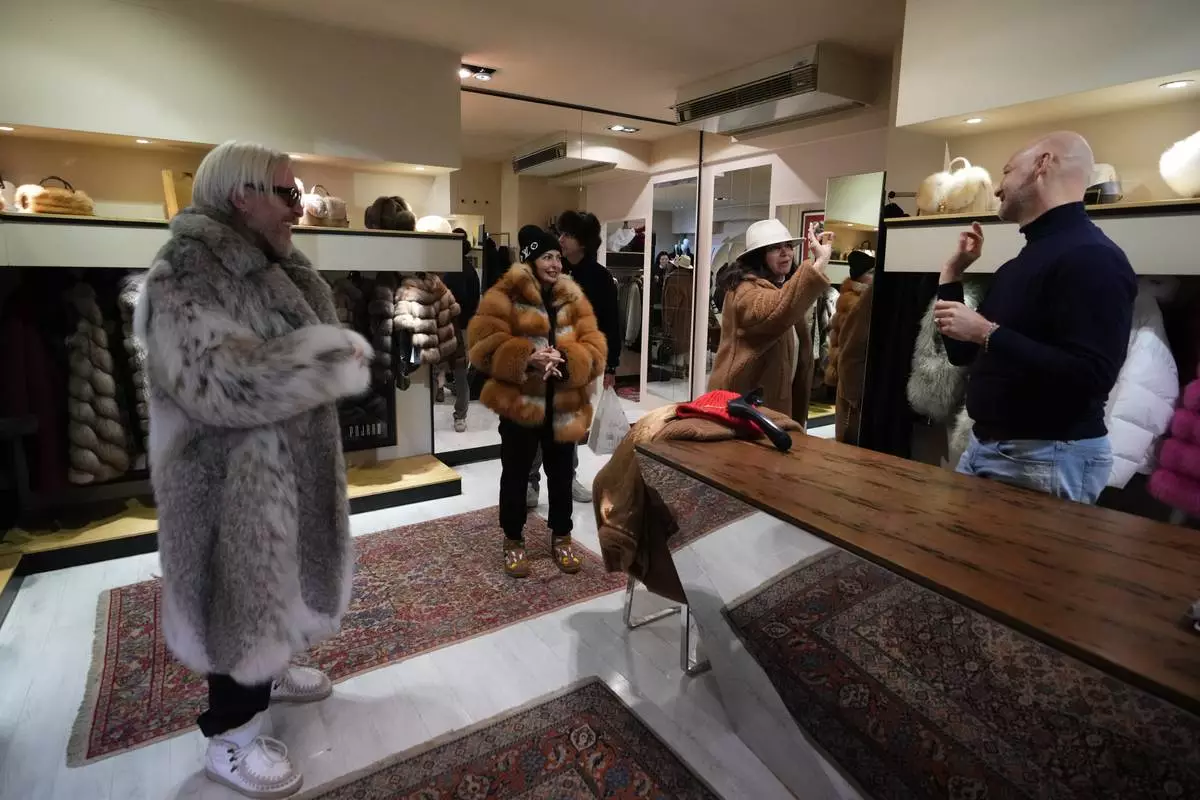 From left, Stefano Vannicola, Silvia Antelli, and Stefania Damiani browse the local branch of Pajaro, a luxury Italian fashion brand, while chatting with sales manager Marco Molinari in Cortina d'Ampezzo, Italy, Saturday, Feb. 14, 2026. (AP Photo/Alessandra Tarantino)