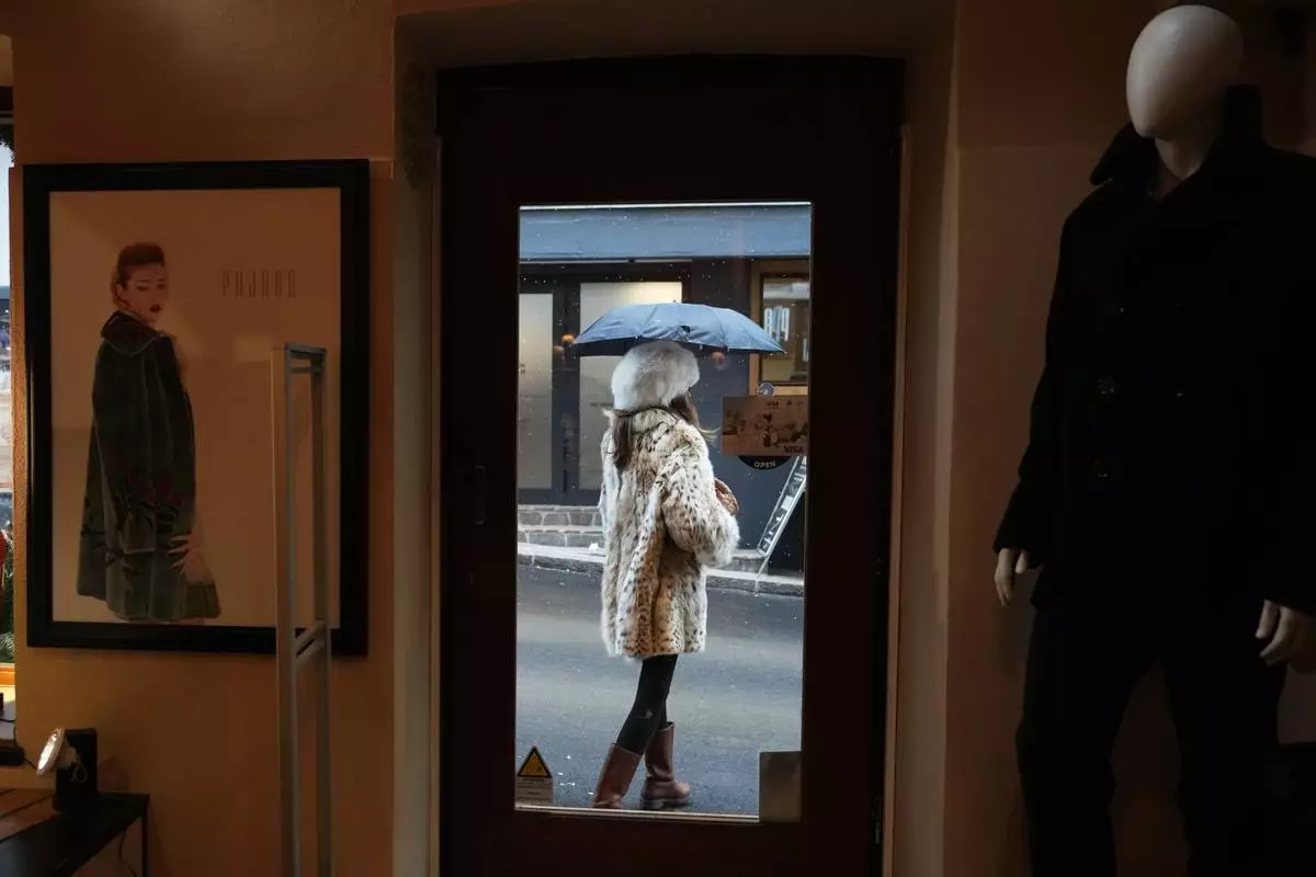 A woman wearing a lynx fur coat leaves Pajaro, a luxury Italian fashion brand in Cortina d'Ampezzo, Italy, Saturday, Feb. 14, 2026. (AP Photo/Alessandra Tarantino)